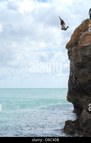 Uomo salta fuori della scogliera di roccia in mare Foto Stock