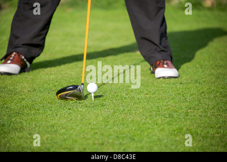 Un golfista risolve la palla sul tee con il suo conducente nella scatola a T Foto Stock
