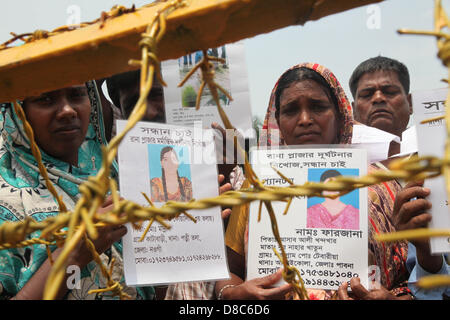 Savar, Dhaka, Bangladesh. Il 24 maggio 2013. Famiglia bengalese membri detengono fino ritratti dei parenti scomparsi creduto di avere morì presso il sito di aprile 2013 Edificio di nove piani crollo in Savar, nella periferia di Dhaka il 24 maggio 2013. Alcuni 290 corpi non identificati sono stati sepolti dopo i campioni di DNA sono stati raccolti in modo che corrispondano a quelli di parenti come l'esercito del Bangladesh avvolto nella sua ricerca Maggio 14, 2013 per gli organismi presso il sito del crollo dell'edificio. Disastri industriali dal novembre hanno ucciso almeno 1.250 lavoratori. Â©Monirul Alam (immagine di credito: credito: Monirul Alam/ZUMAPRESS.com/Alamy Li Foto Stock