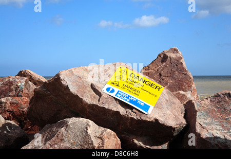 Un segno di pericolo su roccia mare difese a Happisburgh, Norfolk, Inghilterra, Regno Unito. Foto Stock