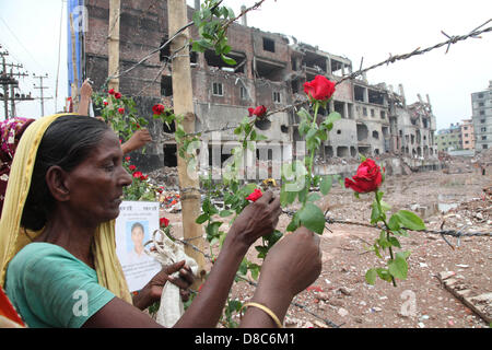 Savar, Dhaka, Bangladesh. Il 24 maggio 2013. Una famiglia bengalese membro di un indumento mancante operatore colloca le rose sul filo spinato come essi rende omaggio alle vittime presso il sito di aprile 2013 Edificio di nove piani crollo in Savar, nella periferia di Dhaka il 24 maggio 2013. Alcuni 290 corpi non identificati sono stati sepolti dopo i campioni di DNA sono stati raccolti in modo che corrispondano a quelli di parenti come l'esercito del Bangladesh avvolto nella sua ricerca Maggio 14, 2013 per gli organismi presso il sito del crollo dell'edificio. Disastri industriali dal novembre hanno ucciso almeno 1.250 lavoratori. Â©Monirul Alam (credito Immagine: © M Foto Stock