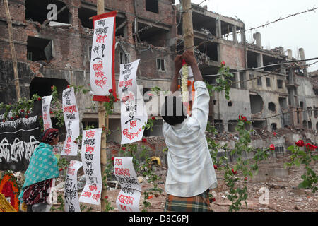 Savar, Dhaka, Bangladesh. Il 24 maggio 2013. Una famiglia bengalese membro di un indumento mancante operatore colloca le rose sul filo spinato come egli rende omaggio alle vittime presso il sito di aprile 2013 Edificio di nove piani crollo in Savar, nella periferia di Dhaka il 24 maggio 2013. Alcuni 290 corpi non identificati sono stati sepolti dopo i campioni di DNA sono stati raccolti in modo che corrispondano a quelli di parenti come l'esercito del Bangladesh avvolto nella sua ricerca Maggio 14, 2013 per gli organismi presso il sito del crollo dell'edificio. Disastri industriali dal novembre hanno ucciso almeno 1.250 lavoratori. Â©Monirul Alam (credito Immagine: © Mon Foto Stock