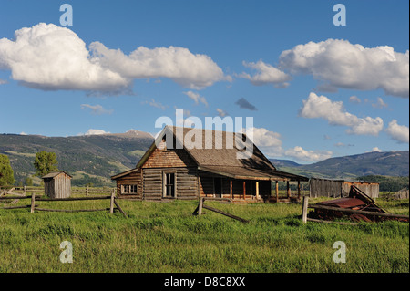 Immagine di un Log Cabin in una prateria, fotografati sotto un cielo blu con pittoresche nuvole bianche. Foto Stock