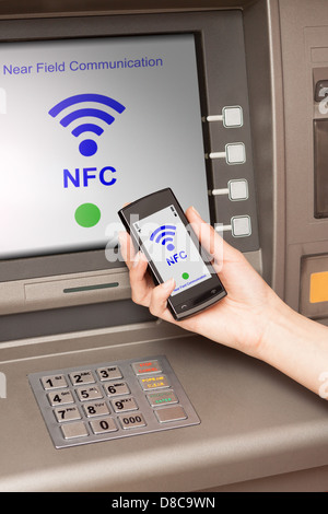 Prelevare denaro dal bancomat con un telefono cellulare un terminale NFC Foto Stock