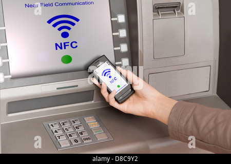 Prelevare denaro dal bancomat con un telefono cellulare un terminale NFC Foto Stock