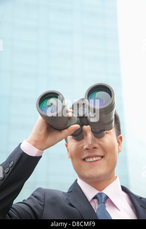 Imprenditore sorridente con il binocolo, Riflessione Foto Stock