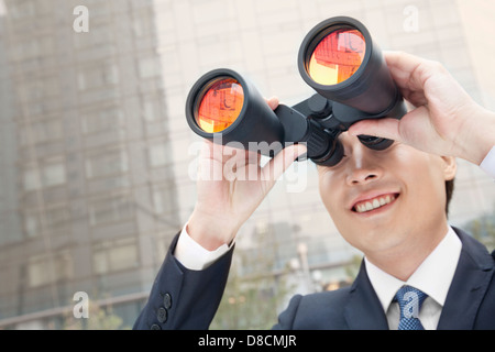 Imprenditore sorridente con il binocolo, Riflessione Foto Stock