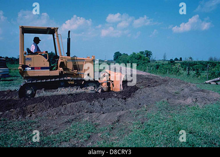 Un bulldozer è visto livellare il terreno, un processo comunemente utilizzato nell'edilizia e nell'agricoltura. La macchina appiattisce il terreno per prepararlo allo sviluppo o alla semina. Foto Stock