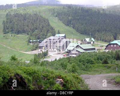 Una montagna incombe su un piccolo villaggio, con la sua presenza torreggiante che crea un contrasto incredibile con il tranquillo villaggio sottostante. Questa immagine enfatizza la grandezza naturale dei paesaggi montani. Foto Stock