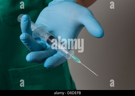 Dettaglio di una mano con il blu guanto in lattice tenendo la siringa Foto Stock