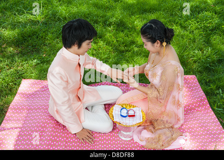 Asian Thai sposa indossa l'anello nuziale al suo Sposo nella cerimonia Thailandese con sensazione di felicità. Foto Stock