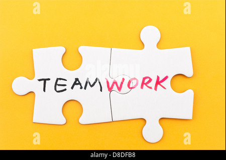 Il lavoro di squadra parola scritta su due pezzi di carta bianca i puzzle Foto Stock