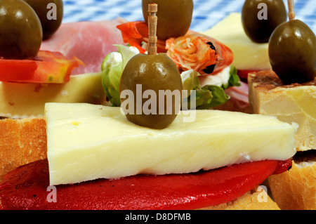 Spagnolo selezione di tapas, peperoncino e formaggio e condito con una verde oliva e servite su crostini di pane in primo piano, Spagna Foto Stock