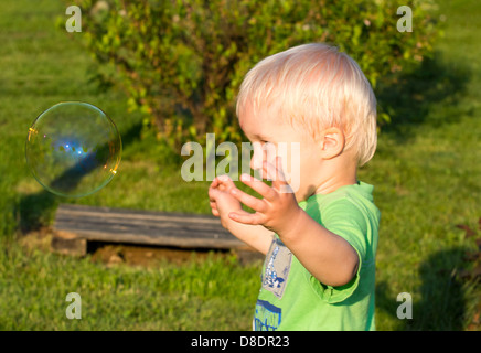 Il Toddler boy divertendosi con bolle di sapone. Foto Stock