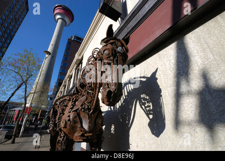 Una scultura a cavallo realizzata interamente con parti riciclate di macchinari agricoli saldate insieme e situata in un angolo di strada nel centro di Calgary, Alberta Foto Stock