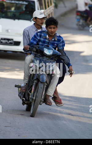 Caotico traffico stradale sulle strade di Mandalay, Myanmar 8- ciclomotore rider è riluttante a lasciar andare una fistfull di dollari Foto Stock