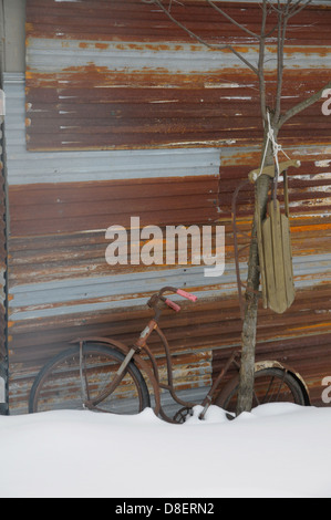 Una slitta e una vecchia bicicletta sedersi al di fuori di un capannone a Warren, Vermont. Foto Stock