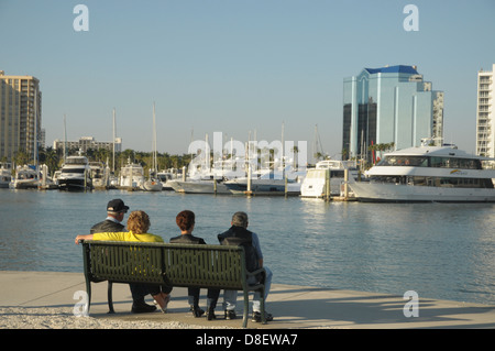 Un gruppo di persone di sedersi su un banco a Sarasota, Florida waterfront. Foto Stock