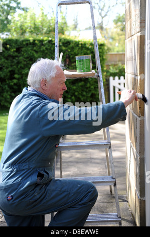 75 anni di pittura pensionato il portico di casa sua nel North Yorkshire, Inghilterra, Regno Unito Foto Stock