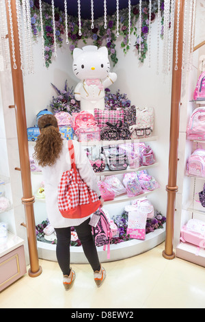 La donna caucasica la scelta di cose da fare per i bambini nella gazzetta Hello Kitty Shinjuku Gate regalo shop, Tokyo, Giappone Foto Stock