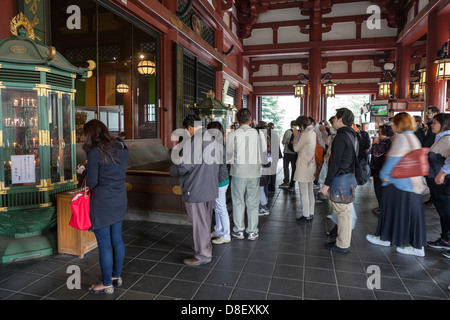 Persone nella parte anteriore del Bodhisattva statua di Kannon nella sala principale di Senso-ji, Tokyo, Giappone Foto Stock