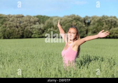 Bella ragazza adolescente felice in un prato verde con i bracci sollevati Foto Stock