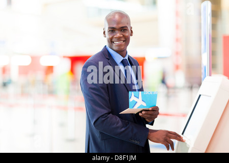 Imprenditore africano usando self service check in macchina in aeroporto Foto Stock