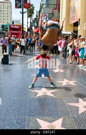 Street performer salti oltre il turista mentre gli spettatori guarda sulla Hollywood Boulevard California Foto Stock