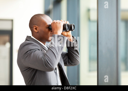 Determinato africana imprenditore americano utilizzando il binocolo in office Foto Stock