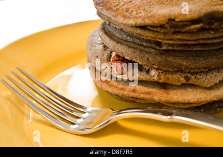 Pila di frittelle di pecan speziate alla zucca su un piatto per la colazione. Primo piano di flapjacks a base vegetale su una piastra gialla. Foto Stock