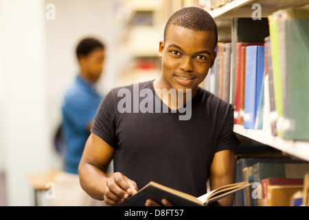 Africa maschio studente di college lettura in biblioteca Foto Stock