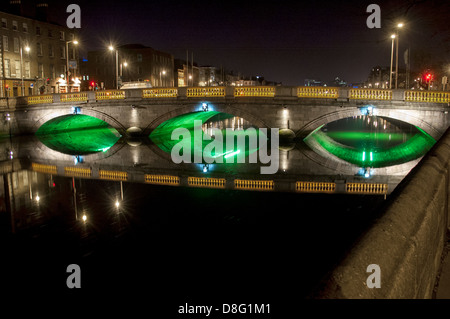 Un ponte che attraversa il fiume Liffey a Dublino, Irlanda è illuminato con luci verdi per festeggiare il giorno di San Patrizio. Foto Stock