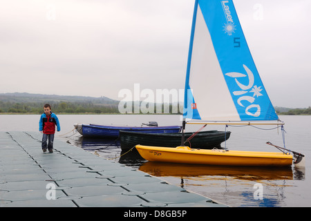 Piccolo Ragazzo su pontone accanto a barche sul Castello Semple loch, Clyde Muirshiel Regional Park, Scotland, Regno Unito Foto Stock