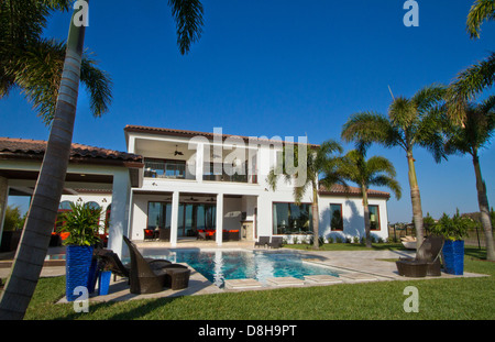 Casa di lusso del valore di diversi milioni di dollari piscina con palme e cielo blu Foto Stock