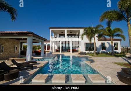 Casa di lusso del valore di diversi milioni di dollari piscina con palme e cielo blu Foto Stock