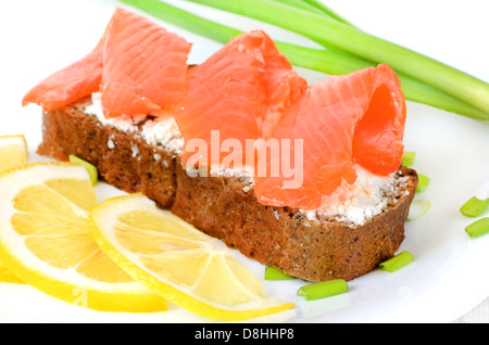 Sandwich con salmone e le fette di limone su una piastra bianca Foto Stock