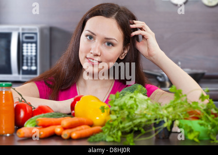 Bella e giovane donna e verdure in cucina domestica Foto Stock