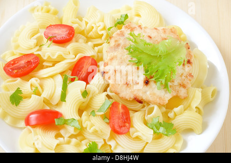 Pasta con pomodori e pollo cotoletta sulla piastra bianca Foto Stock