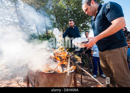 Un ebreo ortodosso uomo getta un sacchetto di pane nel fuoco come parte dei preparativi per le vacanze di Pasqua. Israele Foto Stock