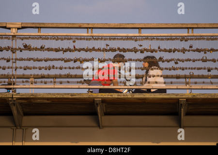 Parigi, Francia. Un giovane si siede sul ponte a Pont des Arts, coperto con lucchetti che simboleggia l'amore ed il rapporto. Foto Stock