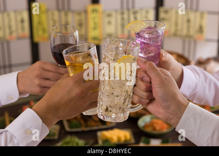 Quattro persone la tostatura gli uni con gli altri con varie bevande a Izakaya Foto Stock