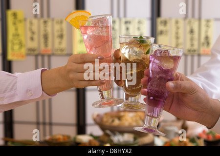 Tre persone la tostatura con vari cocktail presso Izakaya Foto Stock