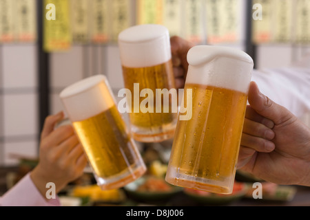 Tre persone la tostatura con birra a Izakaya Foto Stock
