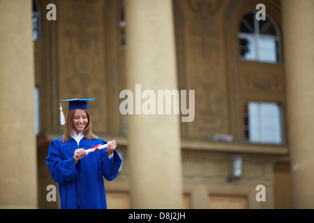 Ritratto di bella studente con diploma in mani sta guardando Foto Stock