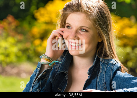 Ragazza giovane e carina a parlare al telefono nel parco Foto Stock