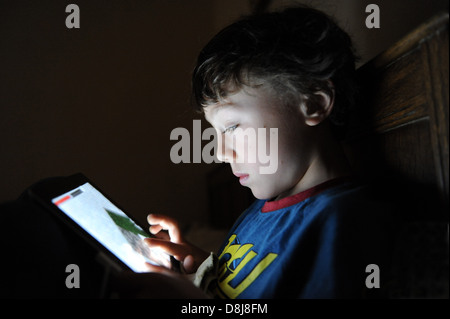 Un 8 anno vecchio ragazzo giocando a un gioco per computer sul suo IPAD Apple nella sua camera da letto a casa. Foto Stock