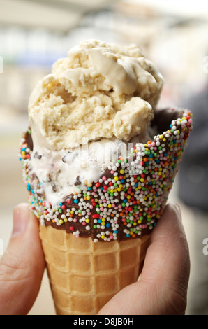 Mano che tiene un gelato con cono Foto Stock