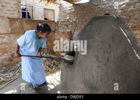 Donna egiziana rendendo il pane piatto in un forno di pietra, Alto Egitto Foto Stock