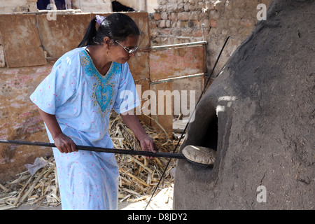 Donna egiziana rendendo il pane piatto in un forno di pietra, Alto Egitto Foto Stock