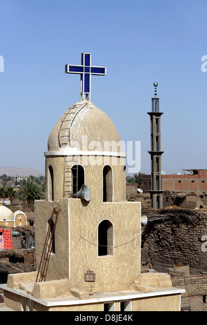 Una croce cristiana su una chiesa copta e cresent sul minareto della moschea musulmana in Alto Egitto Foto Stock